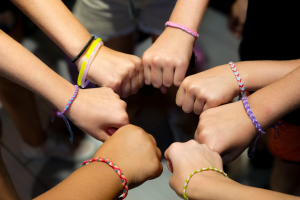 Fiatalok csapatban összeteszik a kezüket.